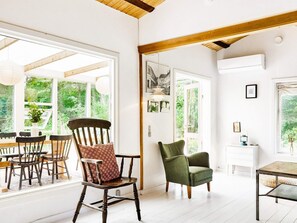 Ein Zimmer mit Holzboden, einem Essbereich mit Stühlen und einem Tisch sowie einem grünen Sessel.