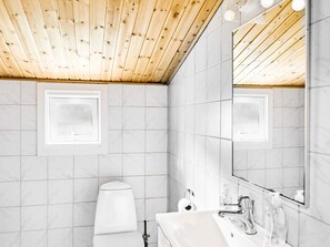 Bathroom features a wooden ceiling, marble walls, and a large mirror above the sink.