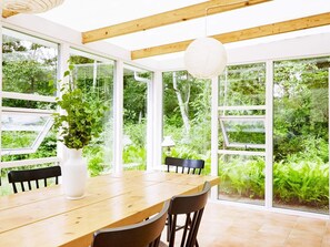 Ein Essbereich mit Holztisch, Stühlen und großen Fenstern mit Blick auf Grünflächen.