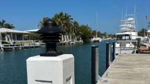 Un port de plaisance avec des bateaux amarrés, une promenade en béton et un bâtiment blanc avec un lampadaire noir.