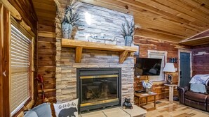 A cozy log cabin interior with a stone fireplace, wooden beams, and a comfortable seating area. - Papa Bear Log Cabin at the Buffalo River (Compton)