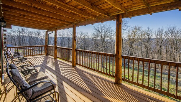 A wooden deck with a railing overlooking a forested area. - Papa Bear Log Cabin at the Buffalo River (Compton)