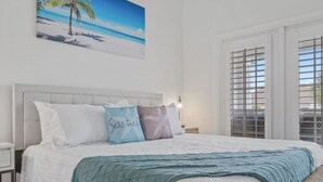 A neatly made bed with a white headboard, a teal throw blanket, and decorative pillows with text. - Pet-Friendly Beach Blessing Steps from the Gulf (Miramar Beach)