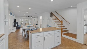 A spacious kitchen with white cabinetry, a granite countertop island, and a wooden staircase. - Pet-Friendly Beach Blessing Steps from the Gulf (Miramar Beach)
