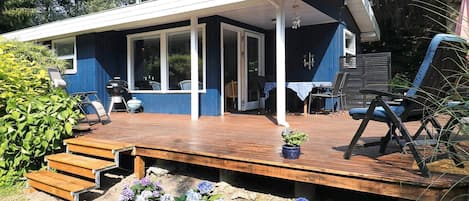 A house with a covered porch, outdoor seating, and a grill.