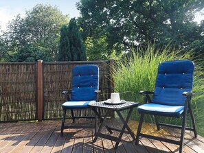 A deck with two blue chairs and a small table, surrounded by a bamboo fence and tall grass. - 5 Person Holiday Home in Tranekaer (Tranekaer)