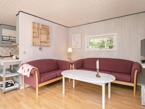 A living room with a red sofa, a white coffee table, and a wooden cabinet with shelves. - 5 Person Holiday Home in Tranekaer (Tranekaer)