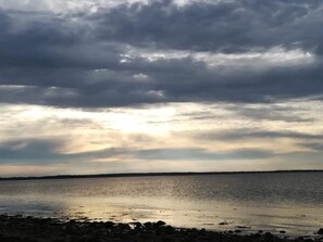 Eine Küstenlandschaft mit ruhiger See, felsigem Ufer und bewölktem Himmel.