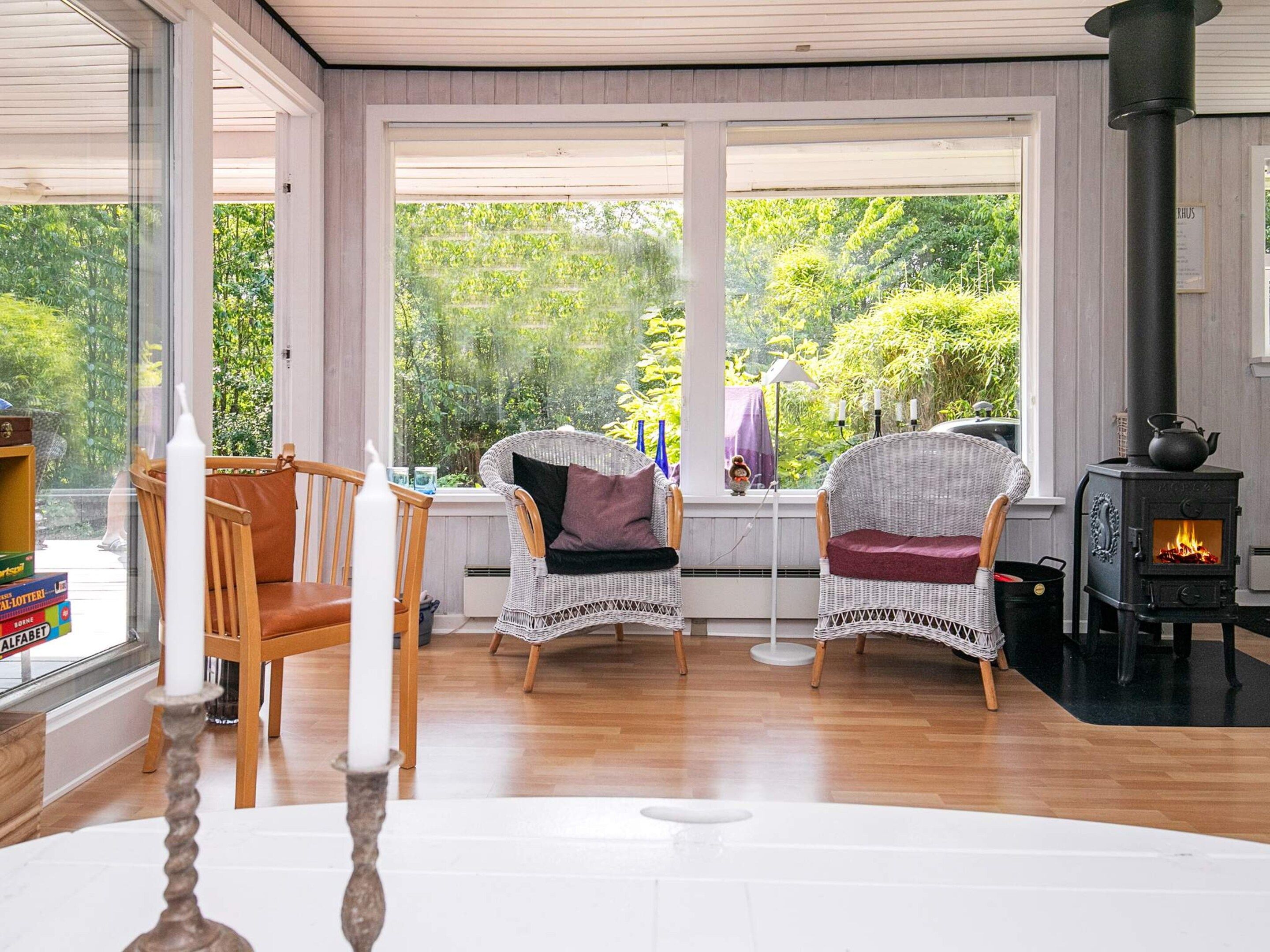 Una habitación acogedora con sillones de mimbre, una mesa blanca y un hogar a leña.