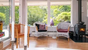 Una habitación acogedora con sillones de mimbre, una mesa blanca y un hogar a leña.