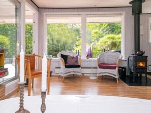 A cozy room with wicker chairs, a white table, and a wood-burning stove.