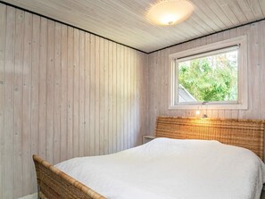 A room with a bed, wooden walls, a window with a view of greenery, and a ceiling light fixture. - 5 Person Holiday Home in Tranekaer (Tranekaer)