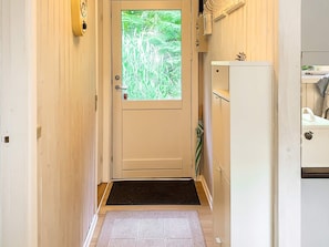 A narrow hallway with a door leading to a room, a small step, and a white cabinet with a plant on top. - 5 Person Holiday Home in Tranekaer (Tranekaer)