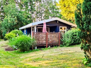 A single-story house with a porch, surrounded by lush greenery. - 5 Person Holiday Home in Tranekaer (Tranekaer)