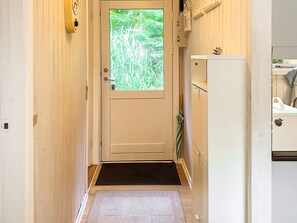 A narrow hallway with a door leading to a room, a small step, and a white cabinet with a plant on top. - 5 Person Holiday Home in Tranekaer (Tranekaer)