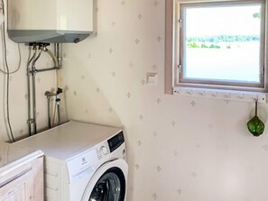A laundry room with a washing machine, a window, and a green hanging ornament. - 5 Person Holiday Home in Loftahammar (Loftahammar)