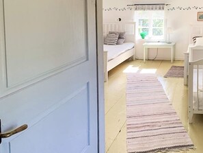 A room with a bed, a small table, and a window with curtains. - 5 Person Holiday Home in Loftahammar (Loftahammar)
