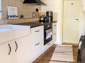 A kitchen with white cabinets, a black countertop, a coffee maker, and a tiled backsplash.