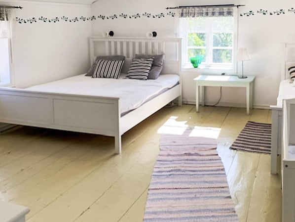 A bedroom with a bed, a bedside table, a lamp, and a window.