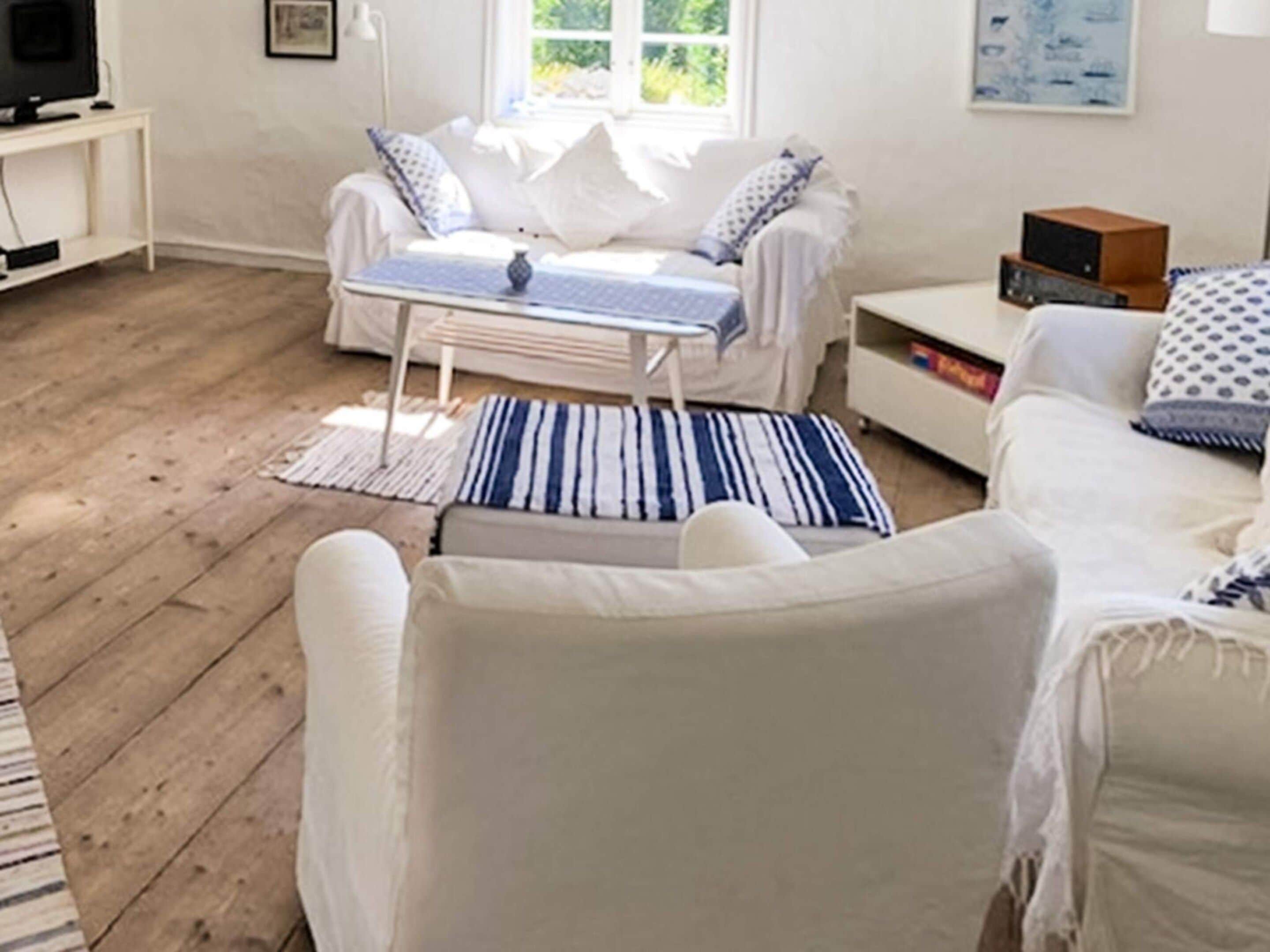 A modern living room with a white sofa, a small white table, and a television on a stand.