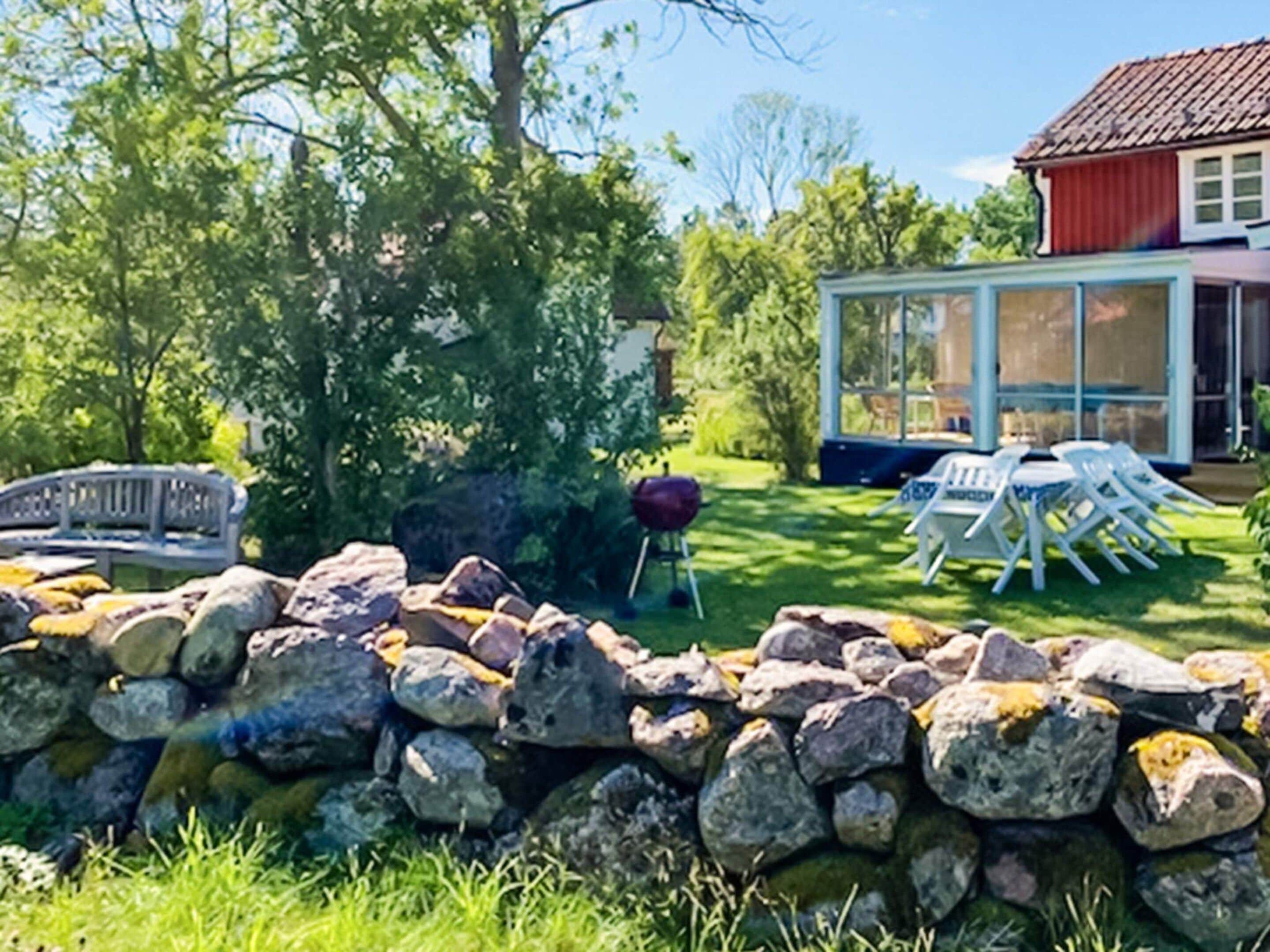 Un muro de piedra, un banco de madera y una estructura de vidrio con asientos al aire libre.