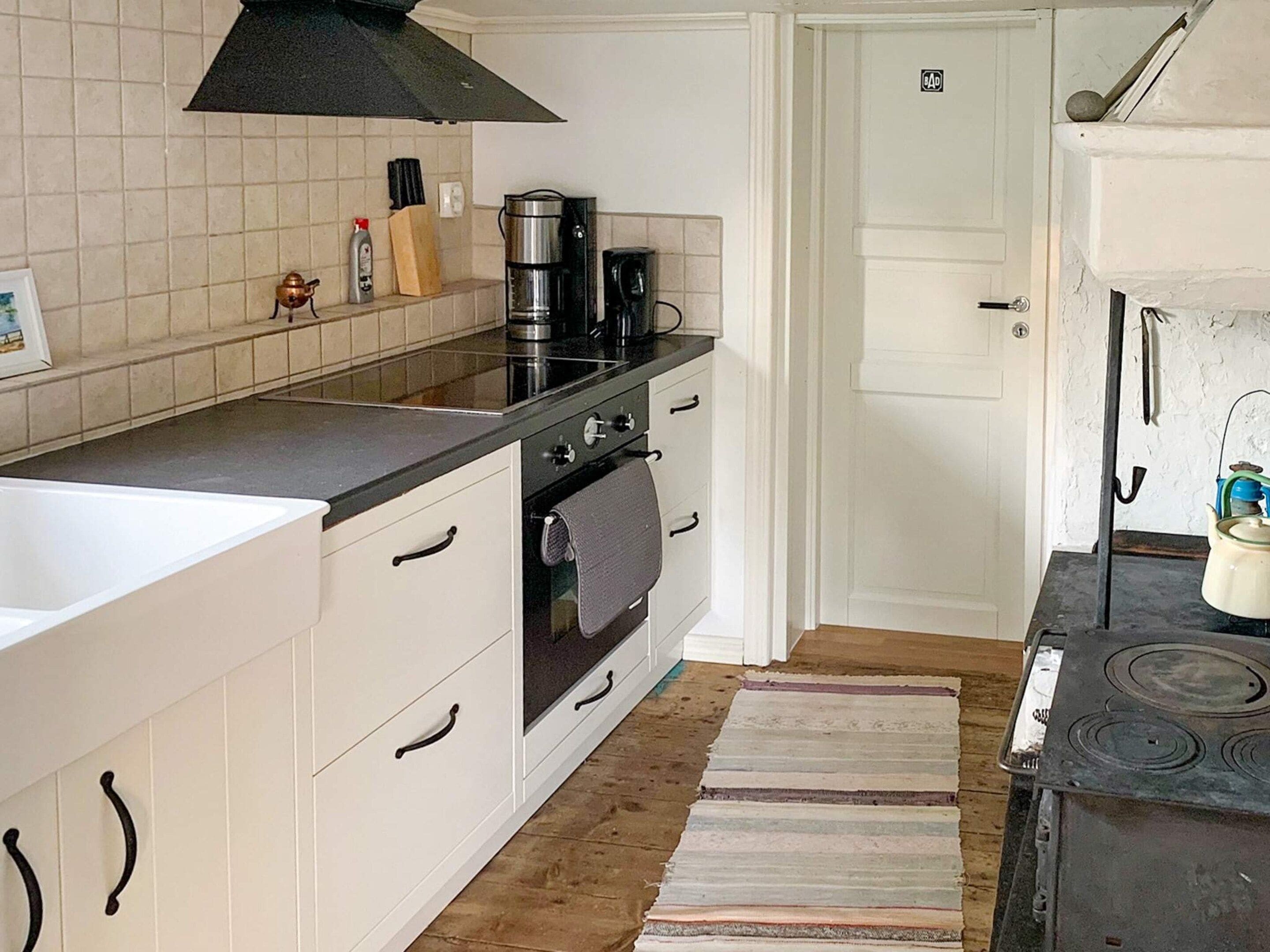 A kitchen with a stove, oven, and coffee maker. There is a door with a number on it.