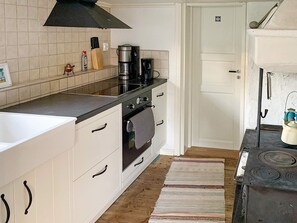 Eine Küche mit Herd, Backofen und Kaffeemaschine. Eine Tür mit einer Nummer ist zu sehen.