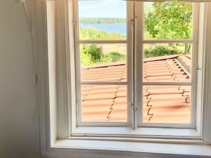 A window with a view of a roof and greenery.