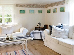A room with two white sofas, a small table with a lamp, and a wall with six framed pictures. - 5 Person Holiday Home in Loftahammar (Loftahammar)