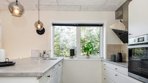 A modern kitchen with a large window, a sink, a stove, and a countertop.