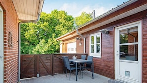 A patio with a table and chairs, a wooden fence, and a brick wall.