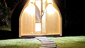 A wooden structure with a peaked roof and a central door, illuminated from within. - 12 Person Holiday Home in Vaeggerlose (Vaeggerlose)