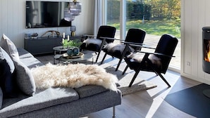 A modern living room with a large TV, black chairs, a grey sofa, and a fireplace. - 12 Person Holiday Home in Vaeggerlose (Vaeggerlose)