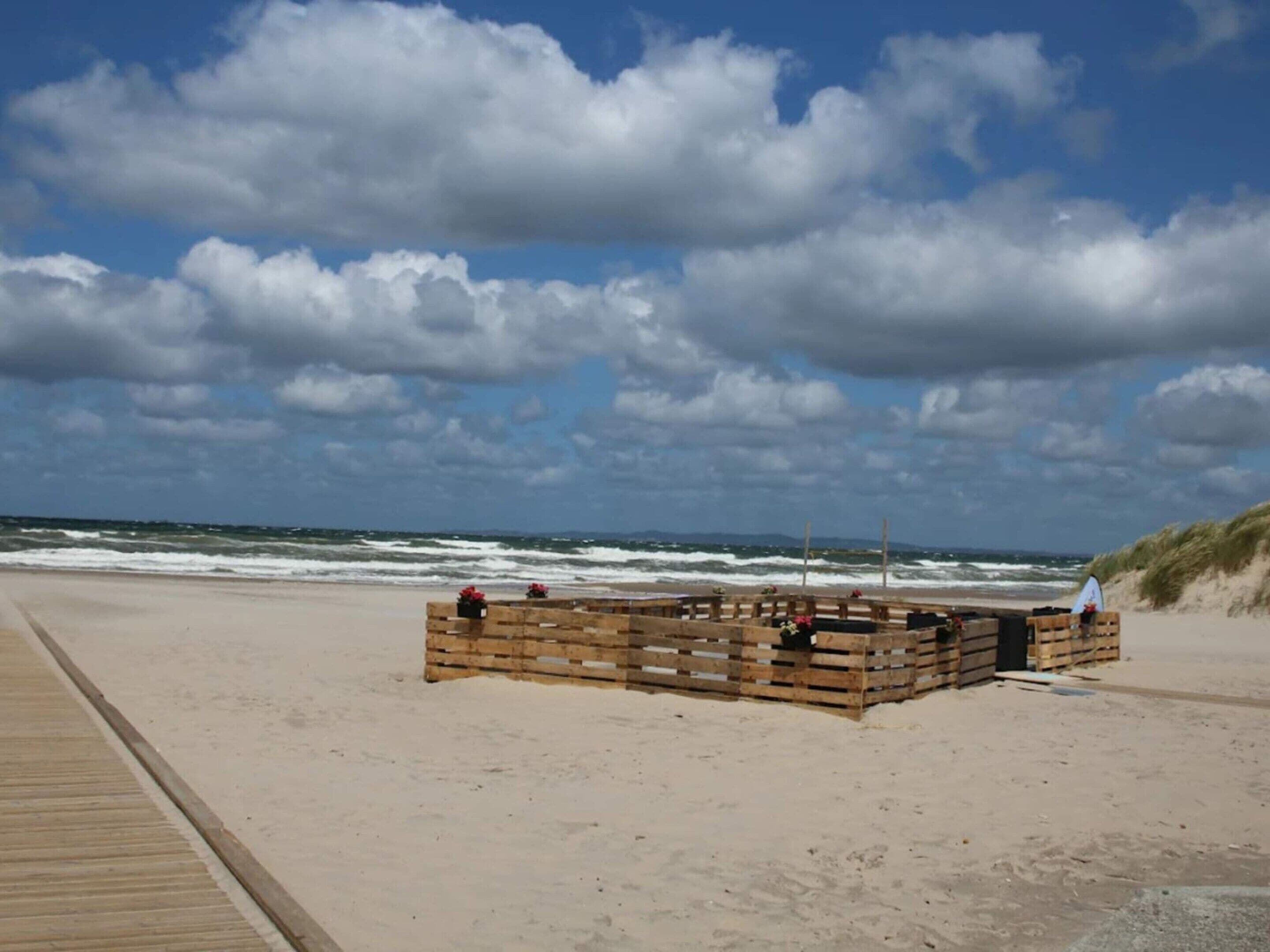 A beach with a wooden structure, possibly a beach hut or a small building, near the water.