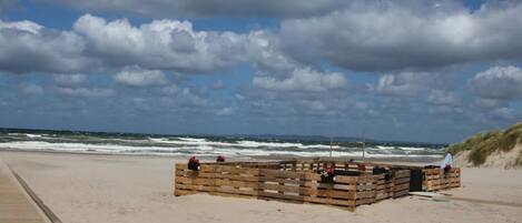 A beach with a wooden structure, possibly a beach hut or a small building, near the water.