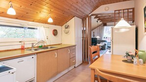 Une cuisine dotée de meubles en bois, d’un lave-vaisselle et d’un coin repas avec une table et des chaises.