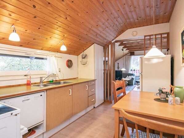 Une cuisine dotée de meubles en bois, d’un lave-vaisselle et d’un coin repas avec une table et des chaises.