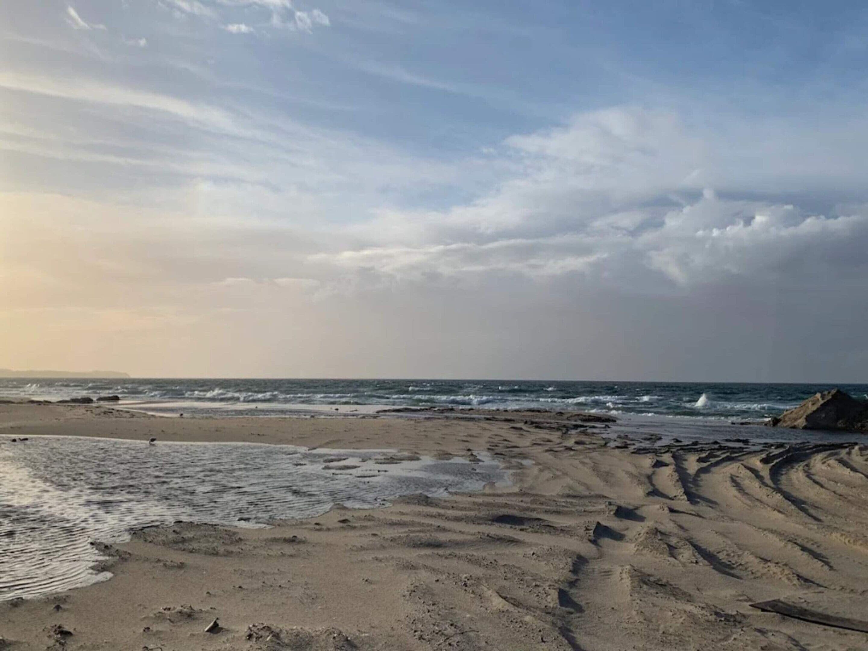 A beach with visible footprints and waves.