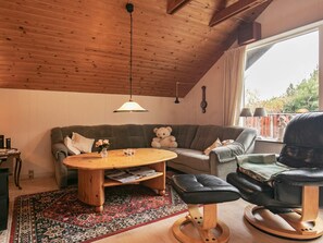 A cozy living room with a wooden ceiling, a round coffee table, a sofa, a rocking chair, and a large window. - 4 Person Holiday Home in Hals (Hals)