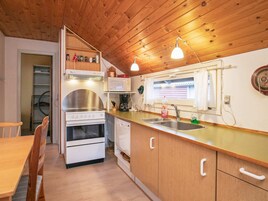 A compact kitchen with wooden cabinets, a stove, a microwave, and a sink.
