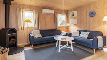 Una sala acogedora con sofá, una mesita, chimenea y ventilador de techo.