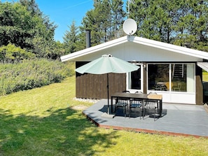 A modern house with a satellite dish, a patio with a table and chairs, and a large sliding glass door. - 6 Person Holiday Home in Fjerritslev (Fjerritslev)