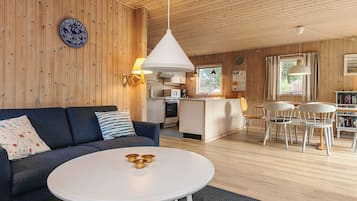 Una sala de estar acogedora con un sofá, una mesa redonda y una cocina con comedor.