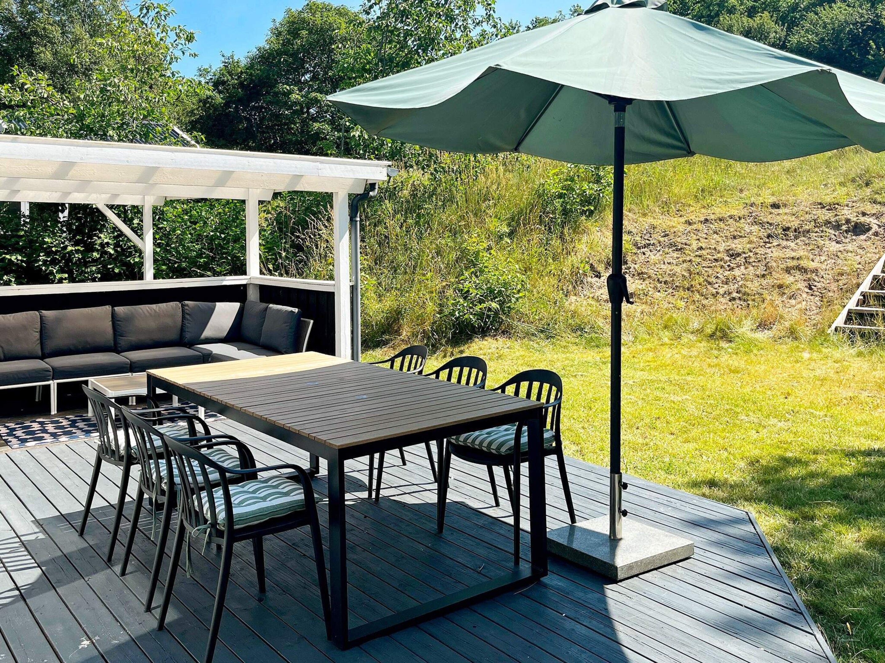 An outdoor deck with a dining table, chairs, and a sofa.