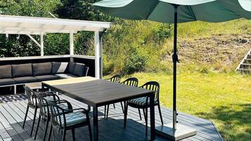 An outdoor deck with a dining table, chairs, and a sofa.