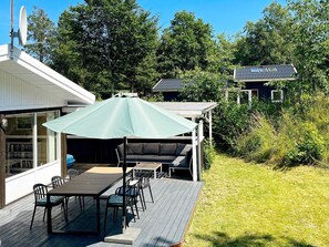 A deck with a table and chairs, a covered seating area, and a view of a house with a satellite dish. - 6 Person Holiday Home in Fjerritslev (Fjerritslev)