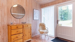 Un interior de madera con un armario, una silla, una puerta y una ventana.