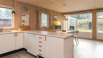 Una cocina moderna con armarios de madera, una isla central y un comedor con vistas al exterior.