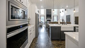 A modern kitchen with stainless steel appliances, a large island with a sink, and a view of the living area. - Family Fun! Private suites, garden games, fire pit & kids loft!  (Broken Bow)