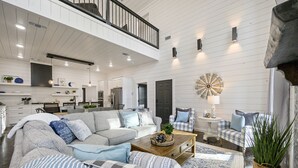 A spacious living area with a large sectional sofa, a coffee table, and a dining area in the background. - Family Fun! Private suites, garden games, fire pit & kids loft!  (Broken Bow)
